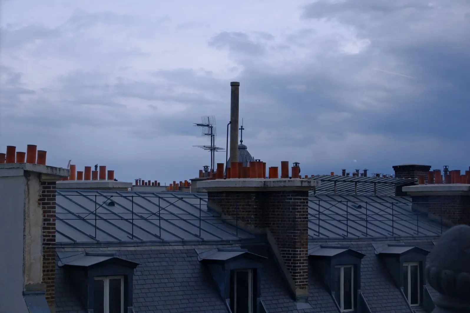 Toits de zinc d'un centre ancien en fin de journée, souches et sorties de toit
