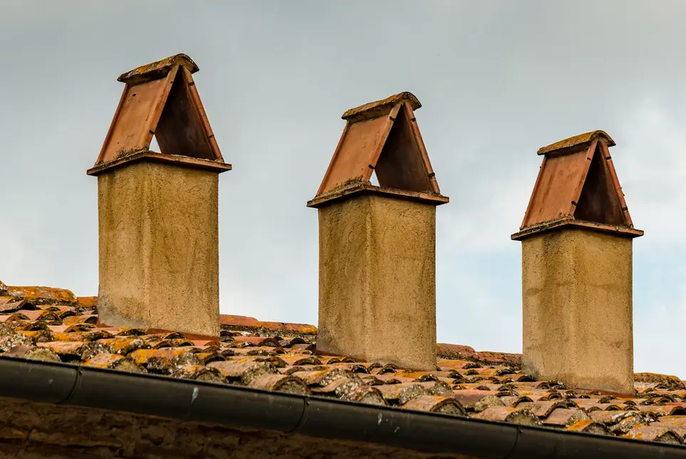 Souches de cheminée en terre cuite sur un rampant, gouttière visible en pied de pente