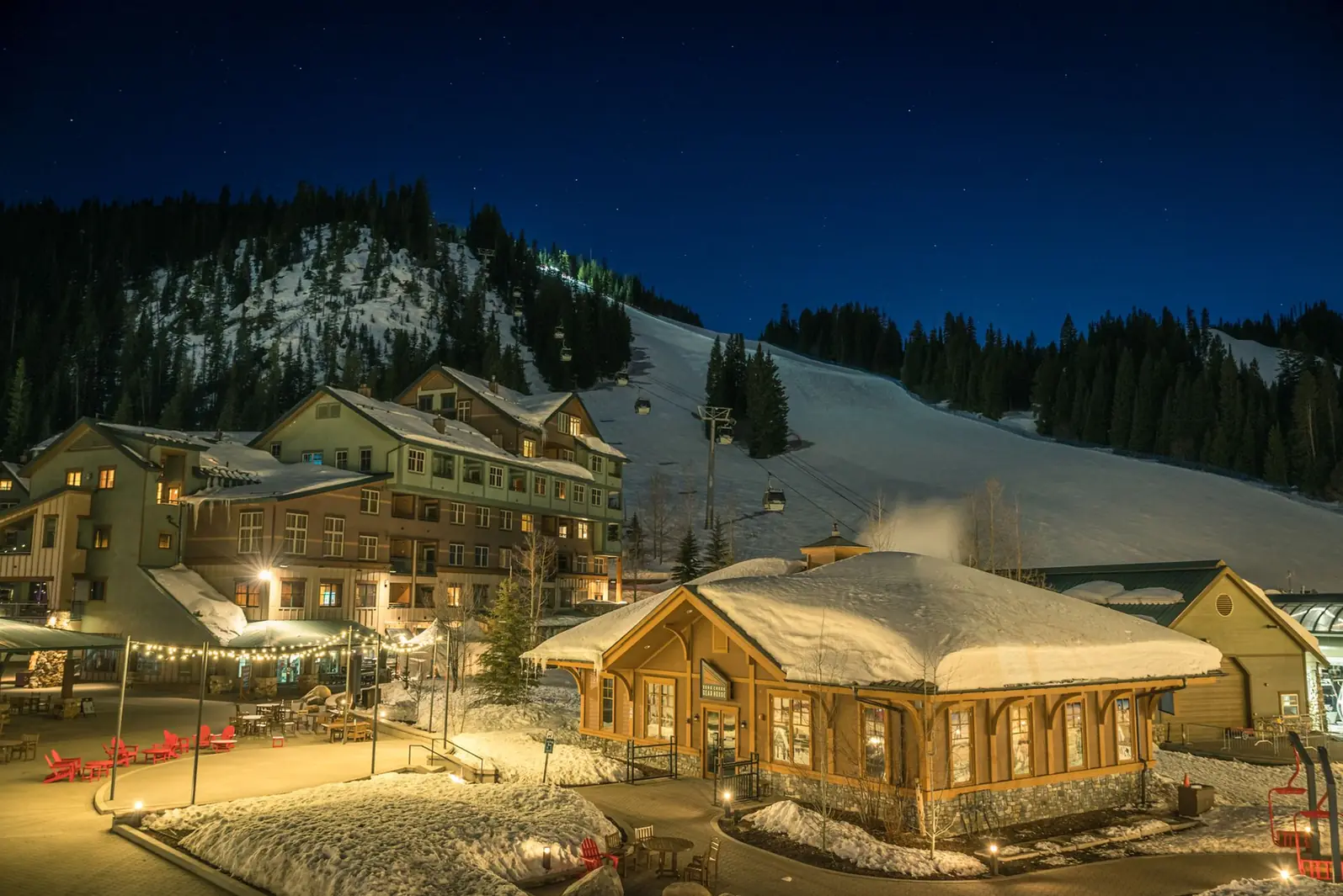 Chalets éclairés au pied des pistes, toitures couvertes de neige