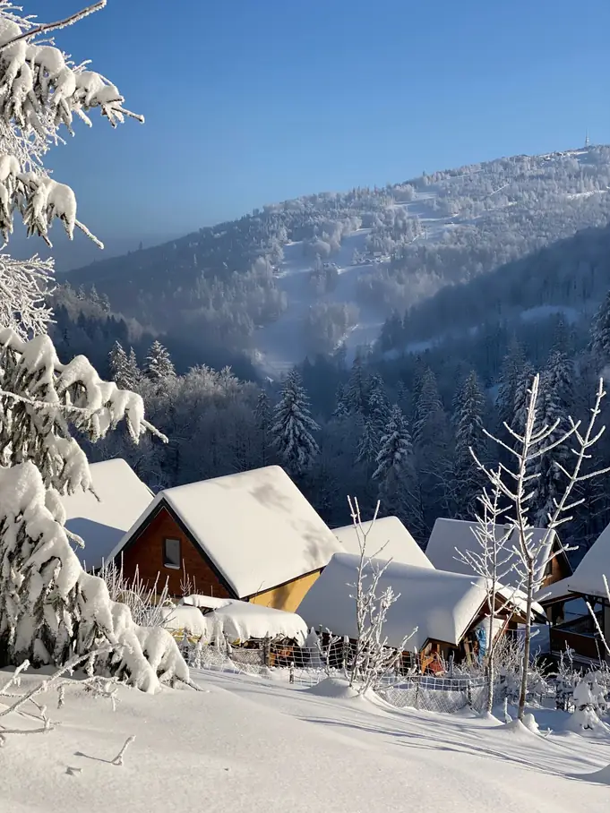 Hameau de montagne sous la neige, sapins et toitures chargées