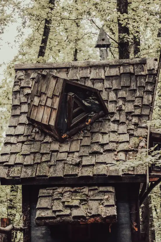 Chalet ancien couvert en bardeaux, lucarne charpentée au-dessus de la façade