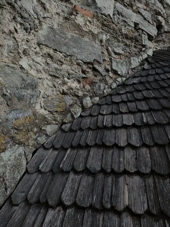 Toiture mêlant lauzes de pierre et bardeaux de bois sur un même pan